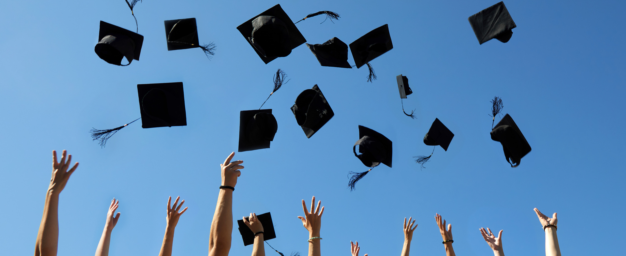 Graduation Caps Thrown in the Air on Blue Sky